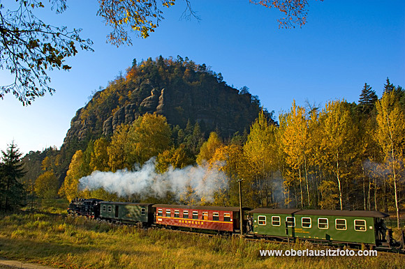 Die Zittauer Schmalspurbahn vor dem Berg Oybin, in sonniger Herbstlandschaft